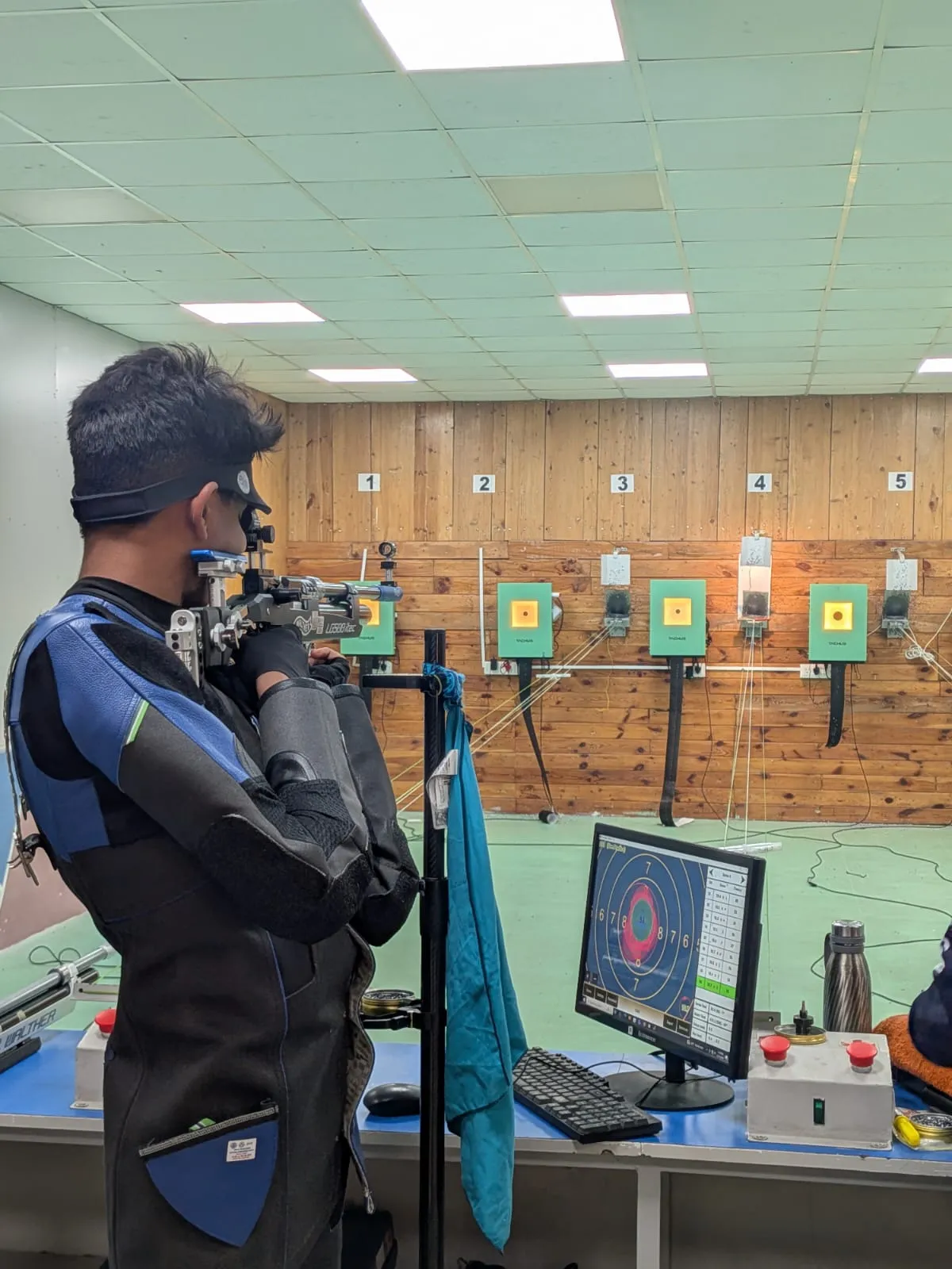 Air rifle shooter training on a Tachus 10 lane with live scores on the monitor