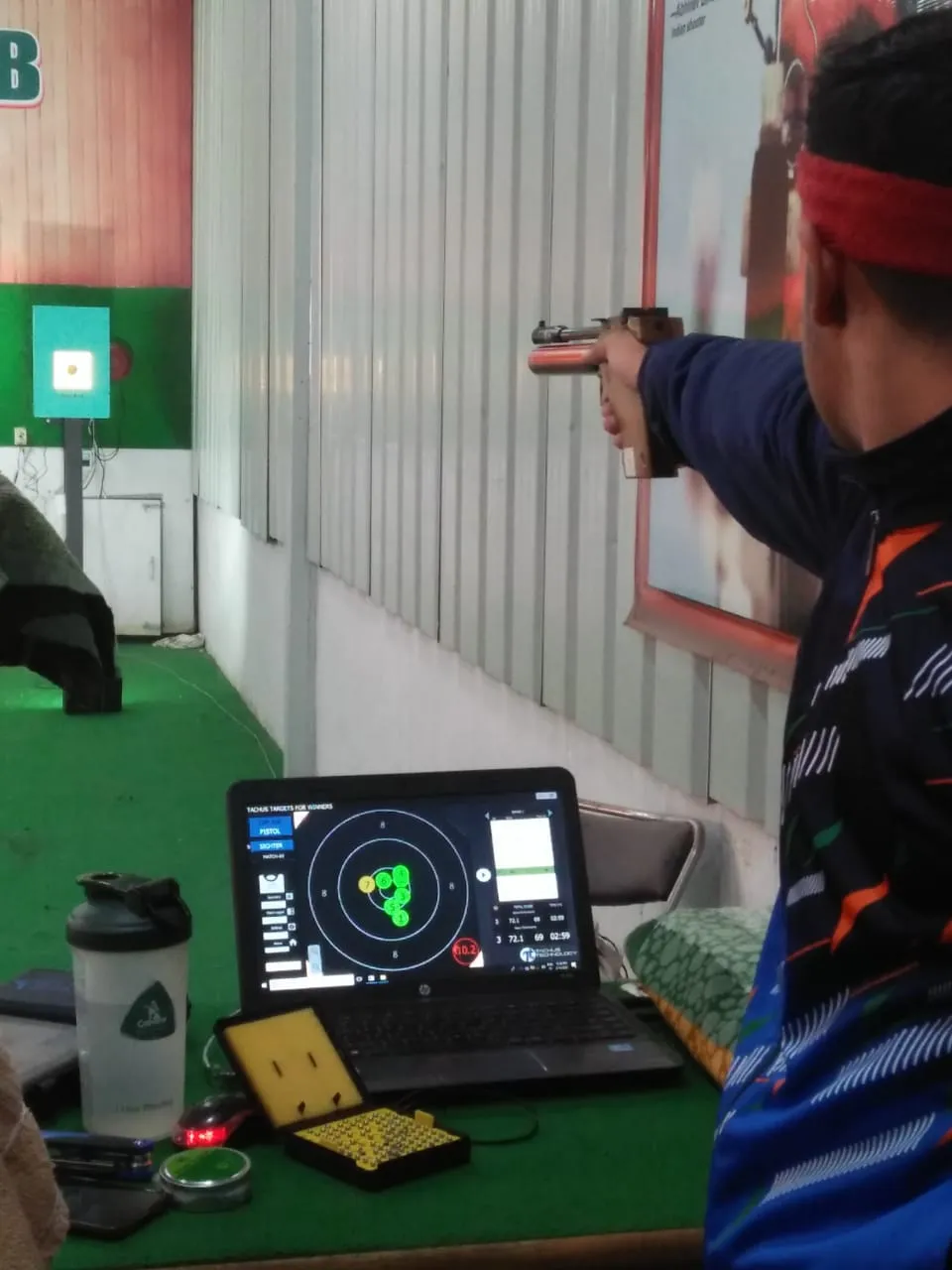 Shooter using a Tachus electronic target with live scoring on a laptop