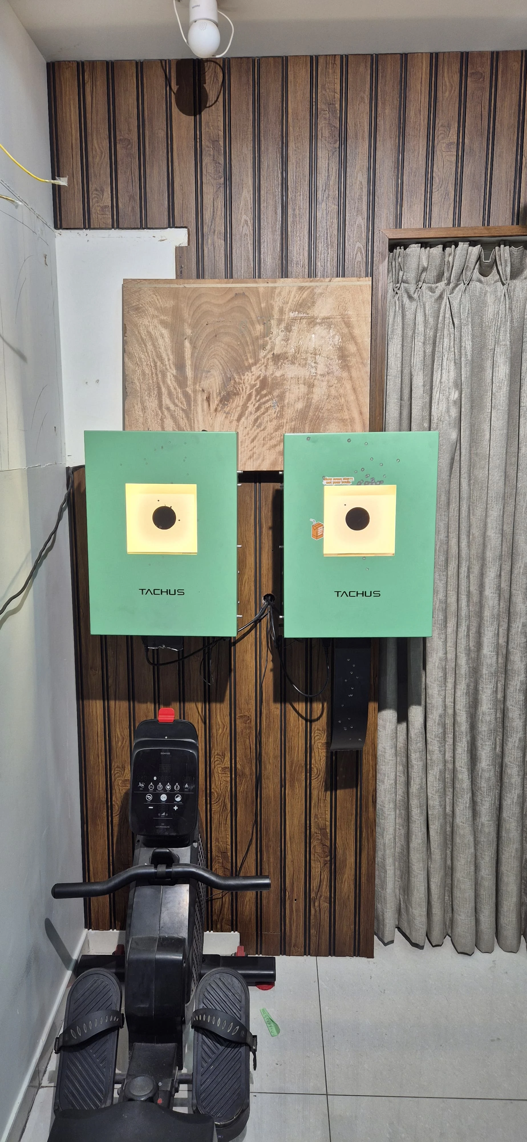 Two illuminated Tachus electronic targets mounted on a wooden wall in a home training space