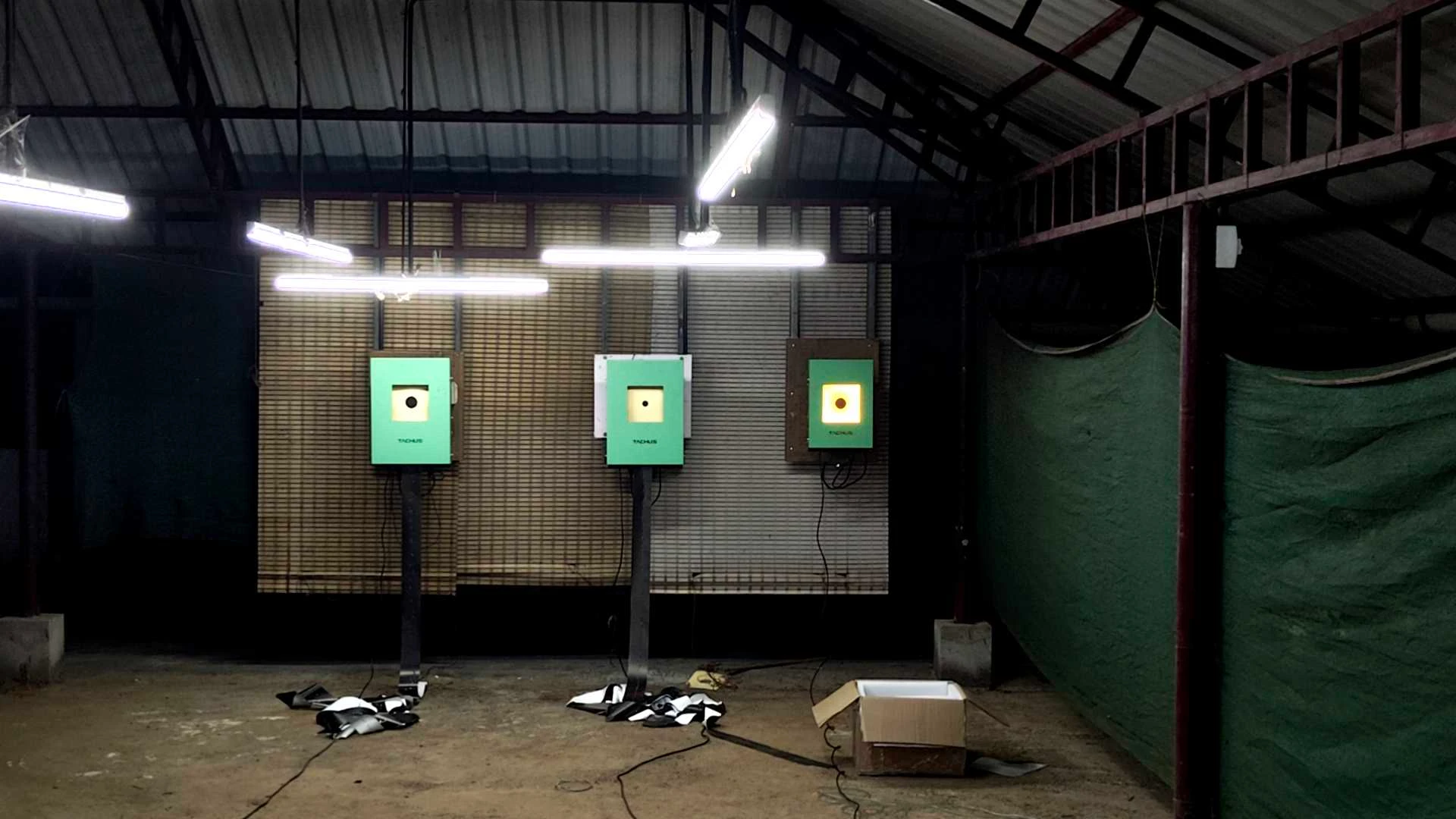 Illuminated Tachus electronic targets in a covered range with green netting along the side