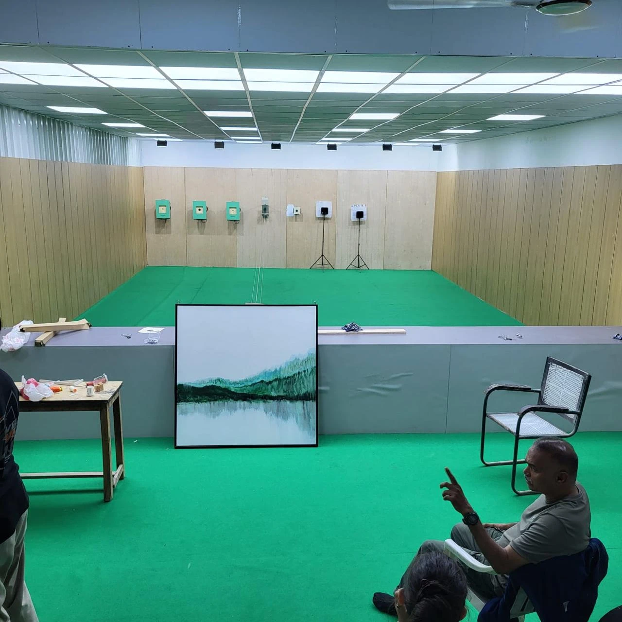 Indoor shooting range with a green floor and Tachus electronic targets along the back wall