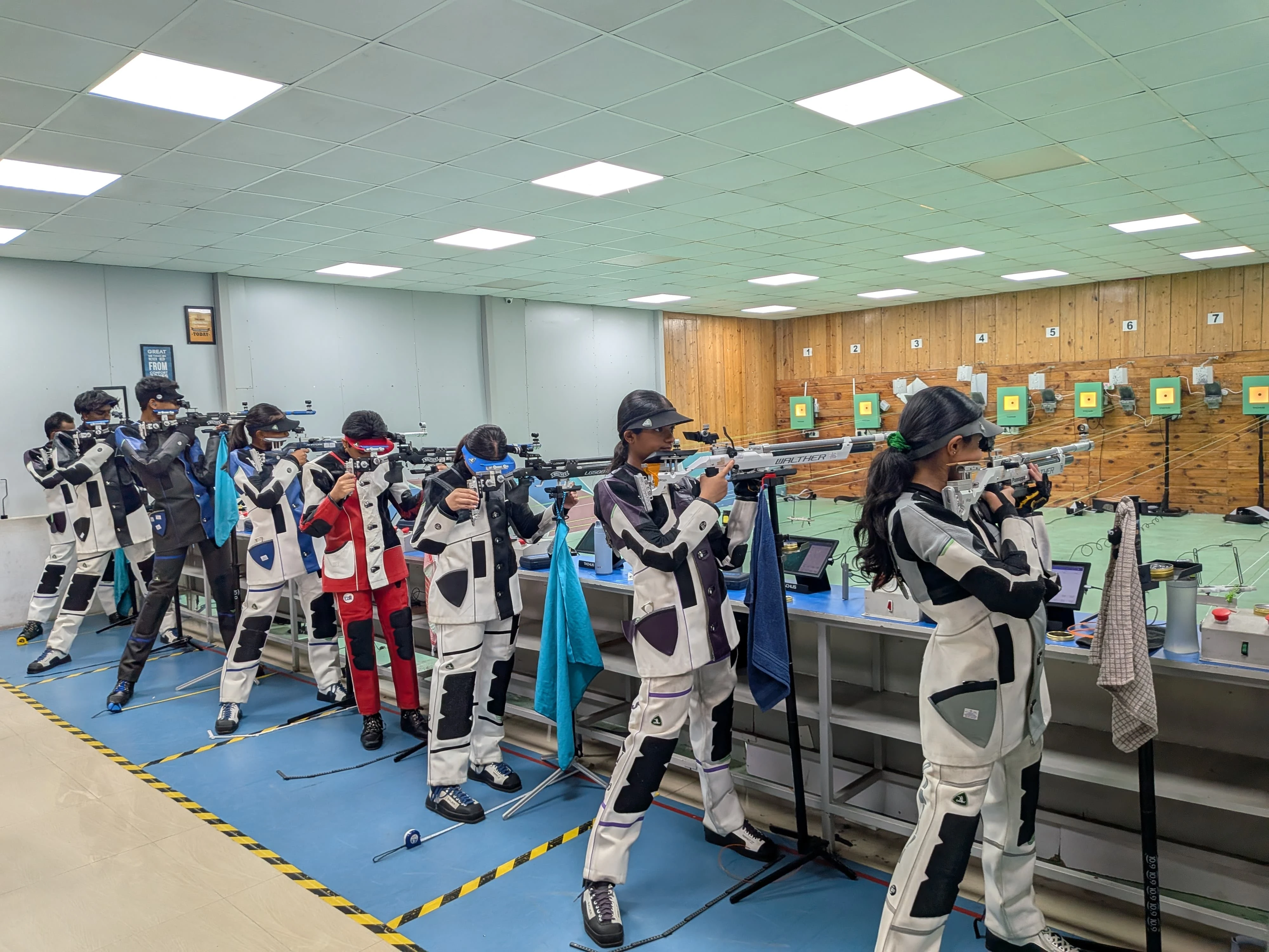 Shooters on the firing line of a Tachus air rifle range with multiple lanes