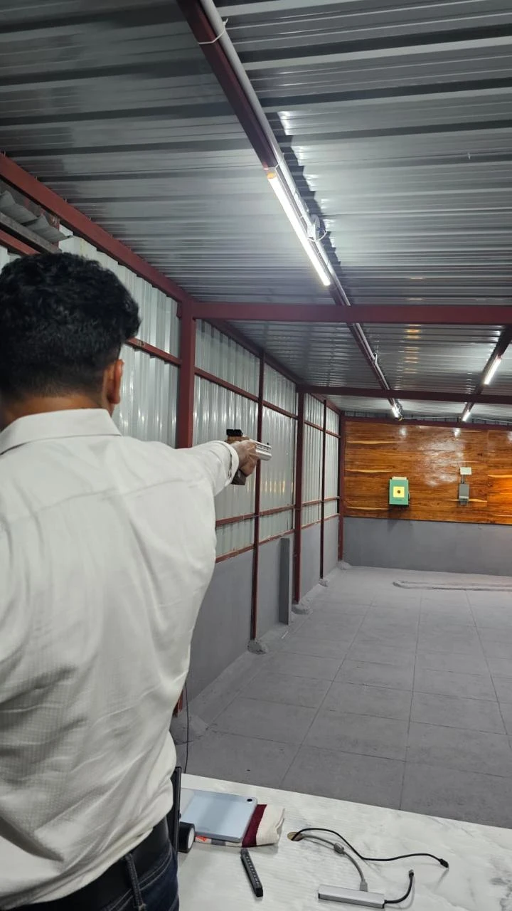 Air pistol shooter aiming at a Tachus electronic target in a covered training lane
