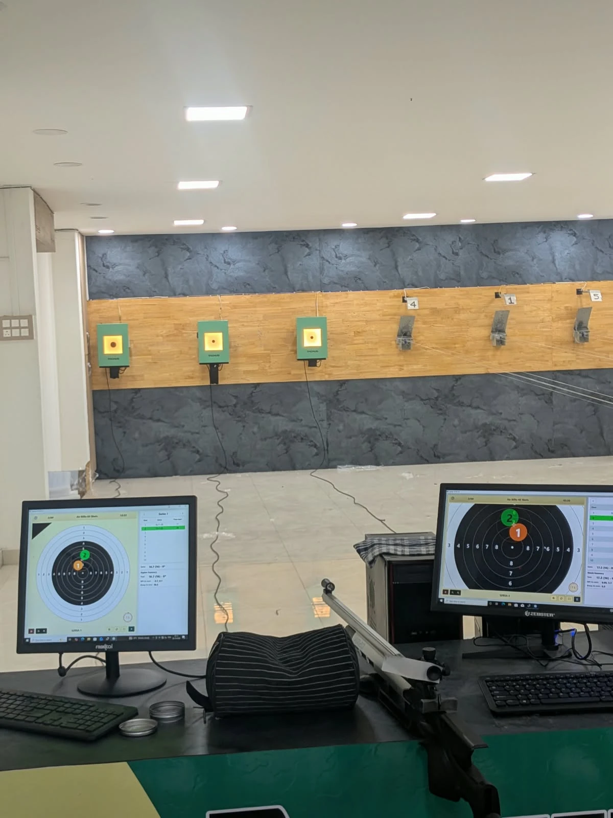 Tachus electronic targets along a wood panelled range wall with scoring monitors at the firing line